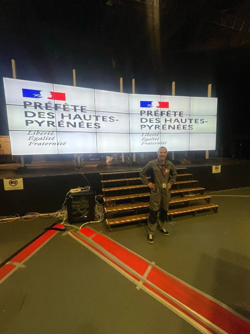 Les deux murs d'images de la salle de contrôle de Lourdes 2026 affichant le logo de la préfète des Hautes-Pyrénées, un membre de l'équipe Easy Multi Display devant la scène